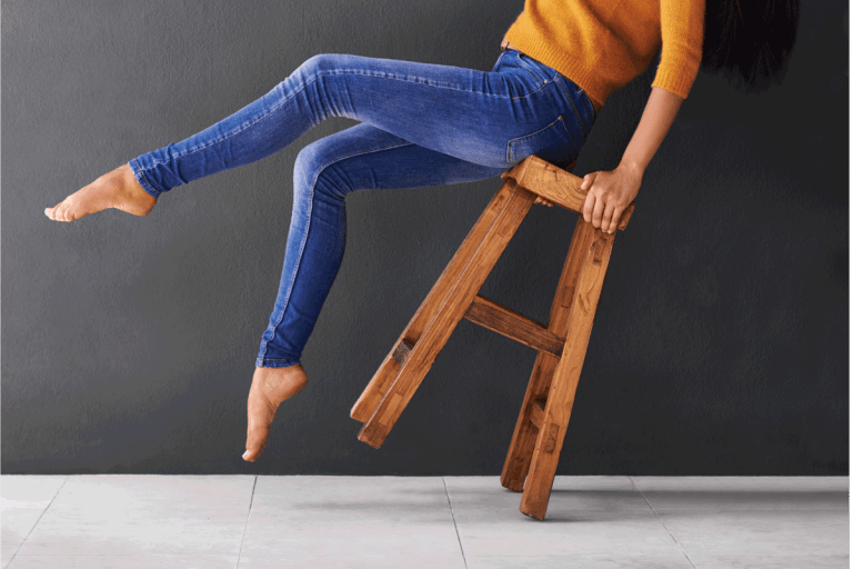 Shot of a happy young woman laughing while leaning back on a stool. How Long Should Skinny Jeans Be