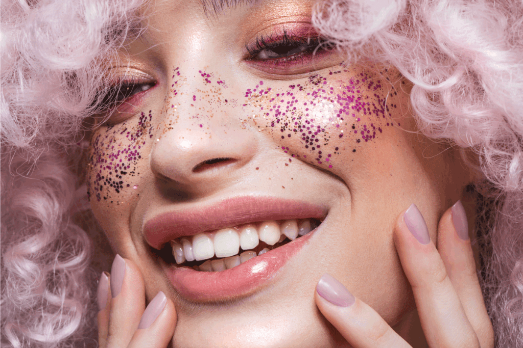 shot of a beautiful girl wearing curly pink wig and glitters on the cheeks. How To Get Body Glitter To Stick