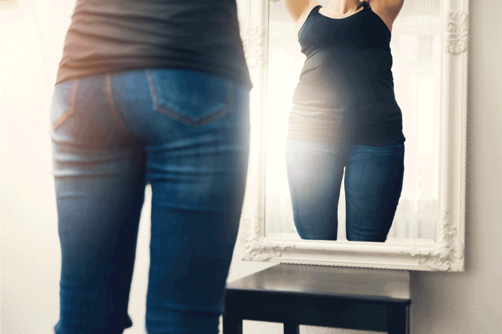 woman looking at the reflection of herself in the mirror, wearing skinny jeans. Do Skinny Jeans Make You Look Taller Or Shorter