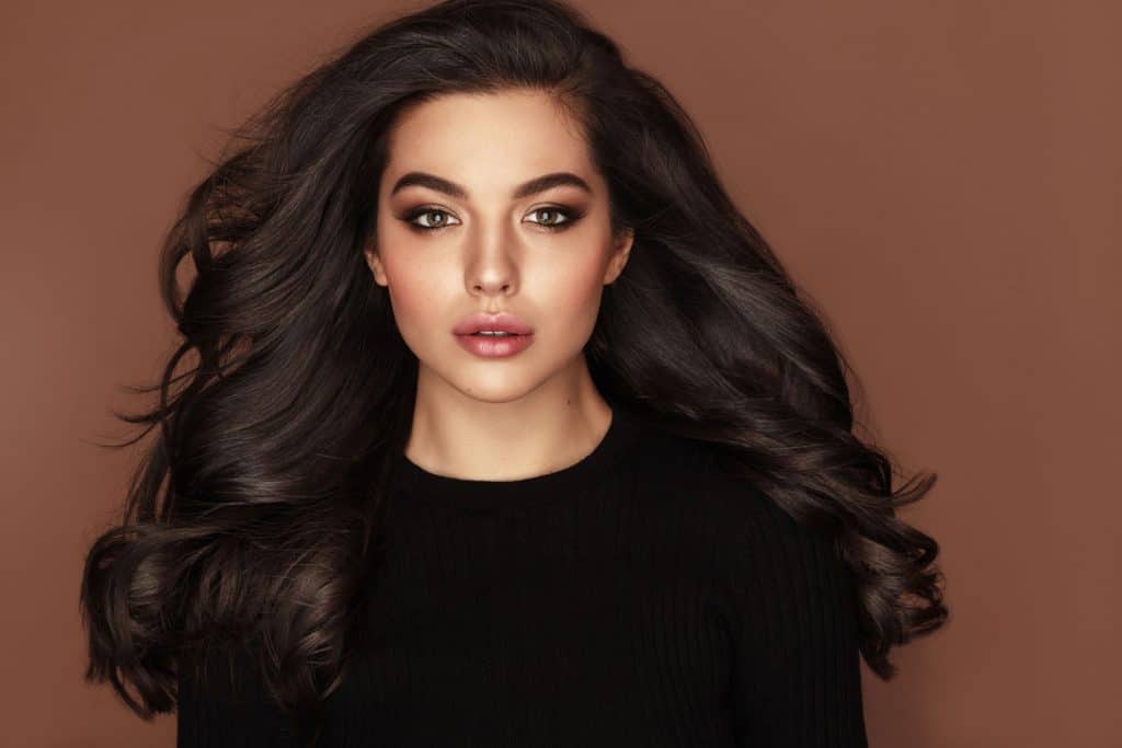 A beautiful latina woman photographed with a vogue expression on a brown background