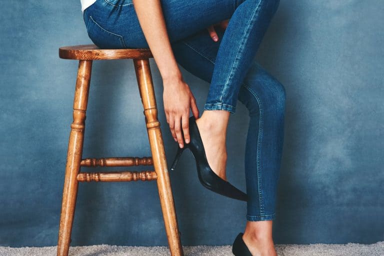 A girl wearing blue jeans and black sandals while sitting on a stool, How To Turn Skinny Jeans Into Flares