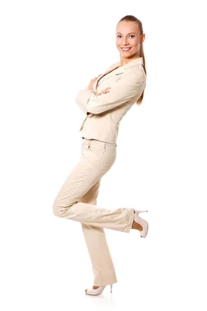 A tall beautiful woman wearing tan tuxedos and pants on a white background