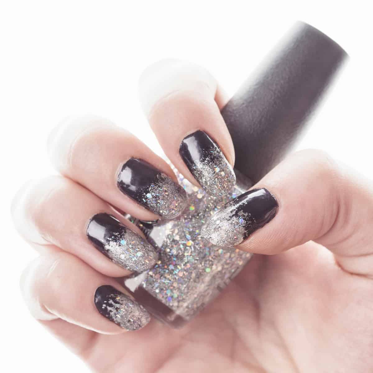 A woman holding gray glitter nails polish 