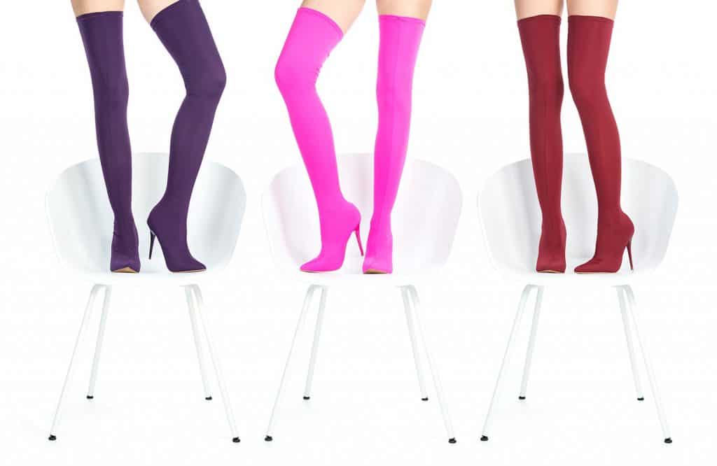 Beautiful female legs in glamorous and colorful thigh-high boots standing on white chairs
