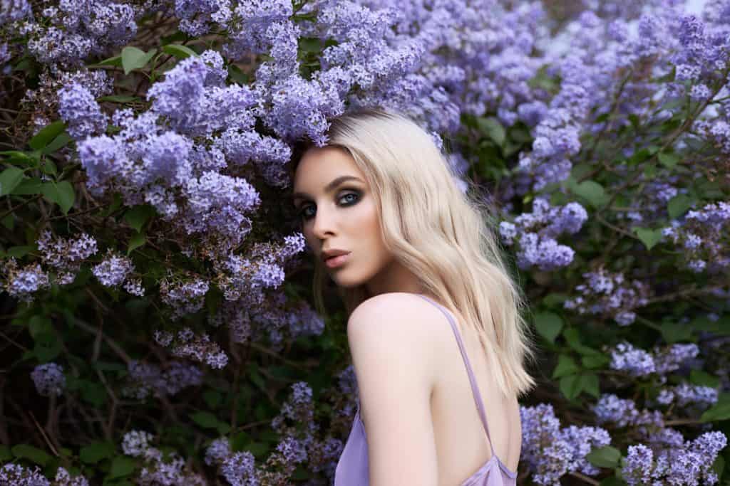 Beauty blonde woman in summer in a lilac Bush. Beauty Portrait of a girl in purple flowers, beautiful makeup