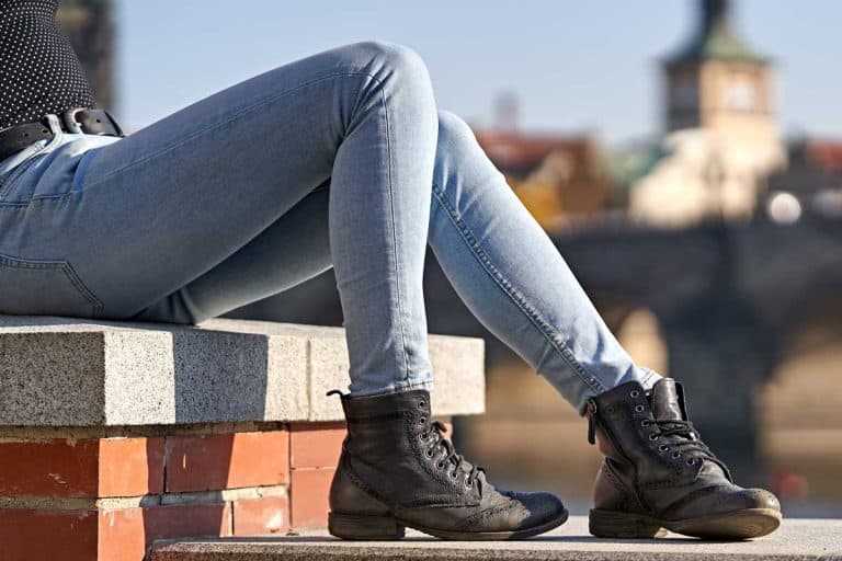 Close-up of a female sitting down on a stone wall and dressing casual skinny jeans, Do Skinny Jeans Get Loose? [With Ways To Prevent Stretching]