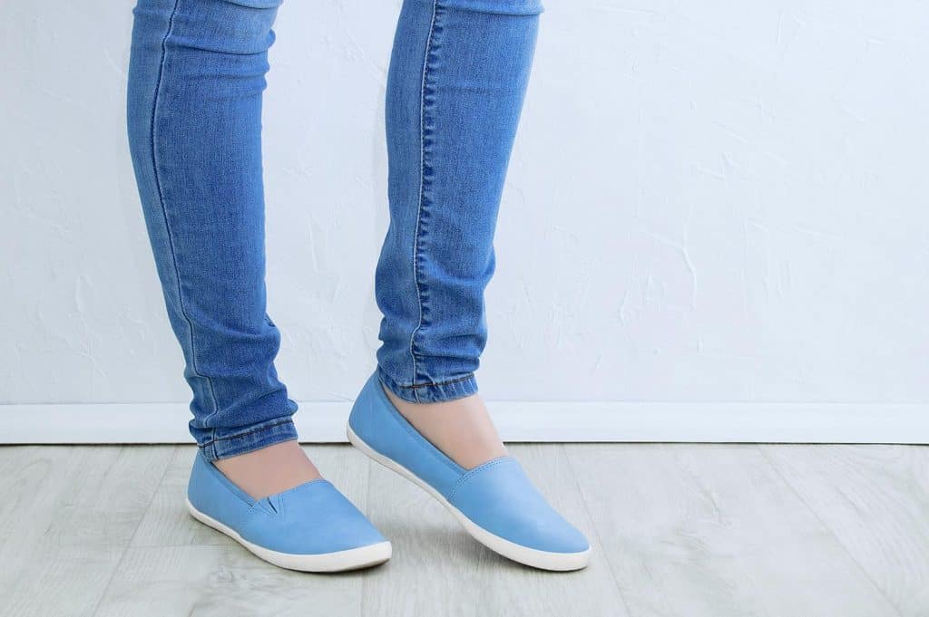 Legs of a caucasian woman in skinny jeans and blue shoes