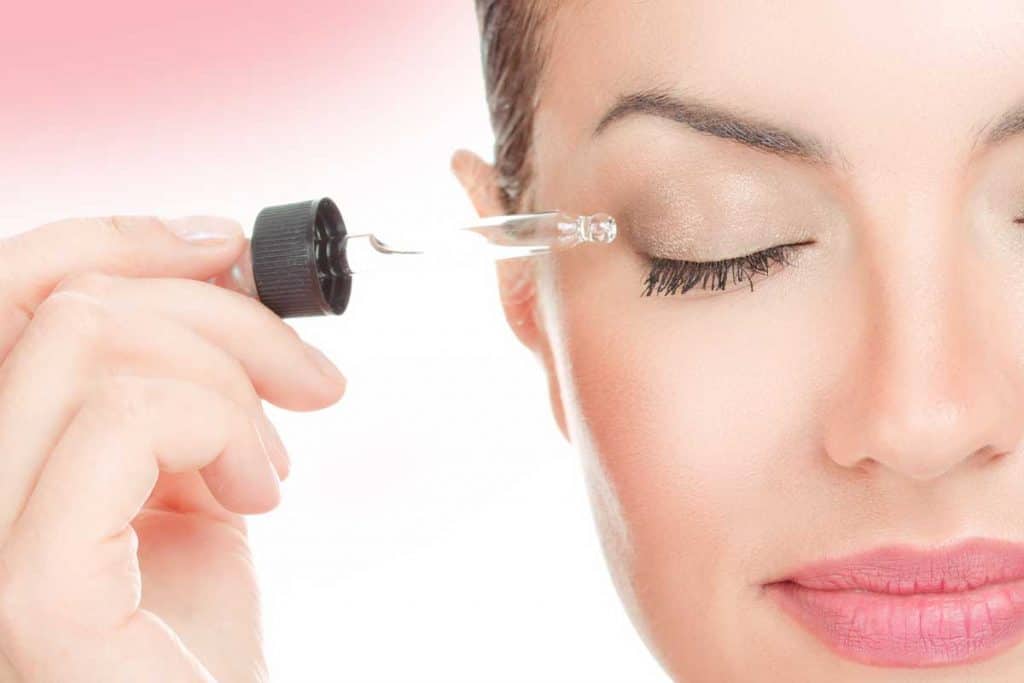 Woman applying serum essence essential oils to her eyelashes for growth strong effect solution, Using Eyelash Serum? Here's What You Must Know!