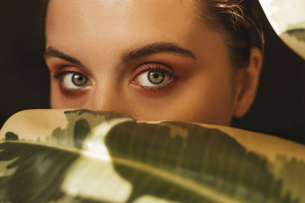 A woman looking at the camera with intent with her green eyes and dark brown eyeshadow, What Color Eyeshadow For Green Eyes?
