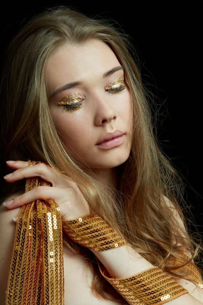 A woman combing her hair while showing her gold eyeshadow