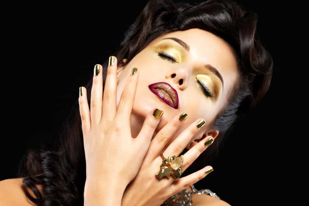 A woman showing her gold finger nails and gold eyeshadow, What Color Lipstick Goes With Gold Eyeshadow?