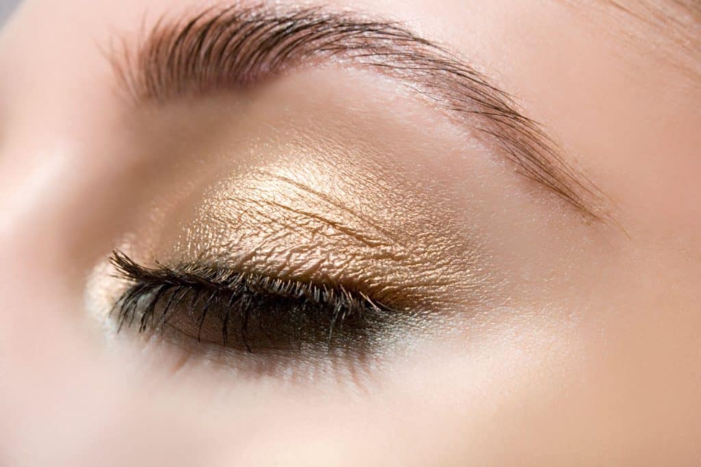 An up close photo of a woman wearing gold eyeshadow