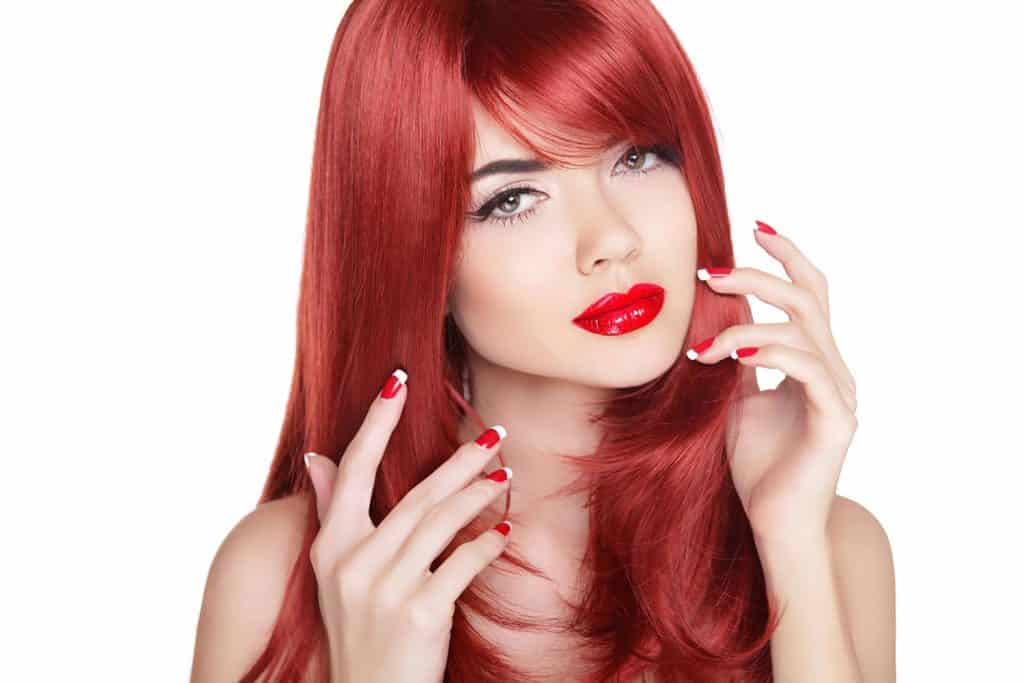 Attractive girl with manicure nails and long shine red hair
