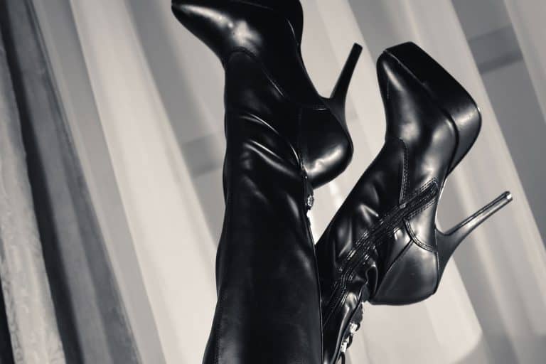 Thigh high boots worn by a woman lying on the couch, What Dress To Wear With Thigh High Boots? [6 Stunning Options Explored!]