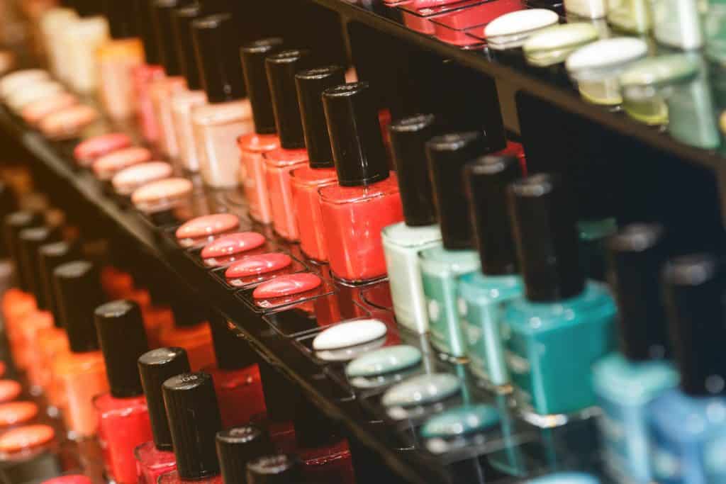 Different colors of nail polish stacked on shelves at the salon