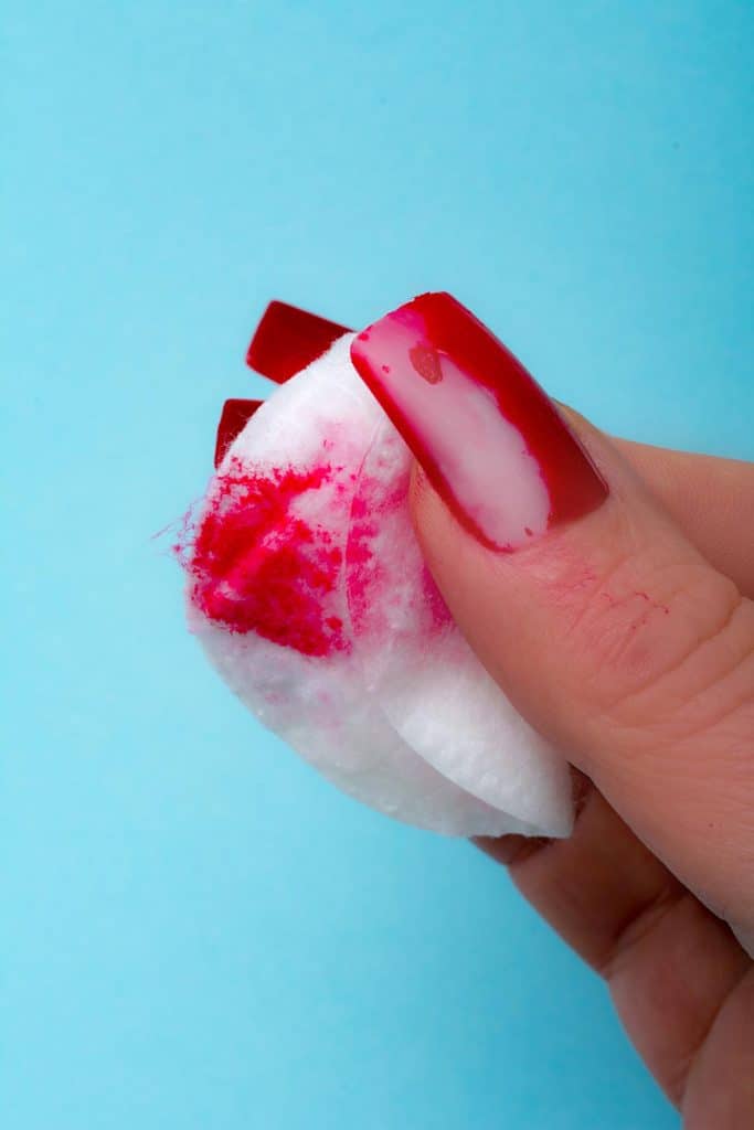 Removing red nail polish with cotton pad