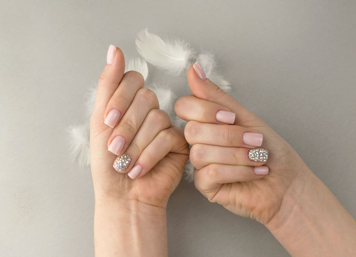 Stylish fashionable women pink manicure with feathers, rhinestones square shape