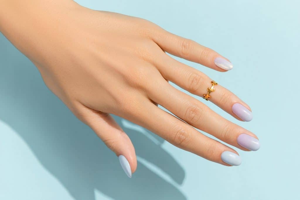 Woman's hands with fashionable manicure on blue background. Summer nail design. Beauty salon concept