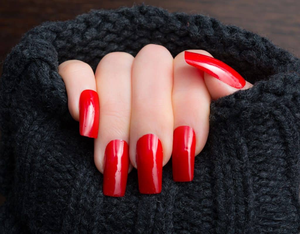 Mature woman showing off her new warm red manicure and dark gray woolen sweater
