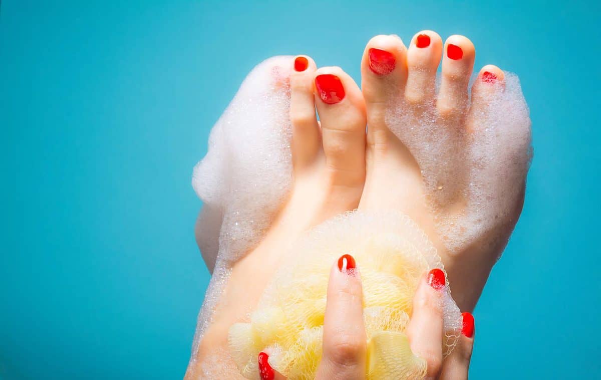 Feet of a young girl with red nails in a thick foam