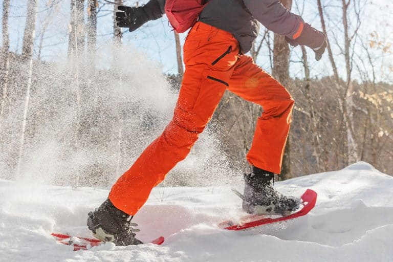 Winter sport outdoor exercise man running in snow in snowshoes having fun, What Kind Of Pants To Wear In The Snow