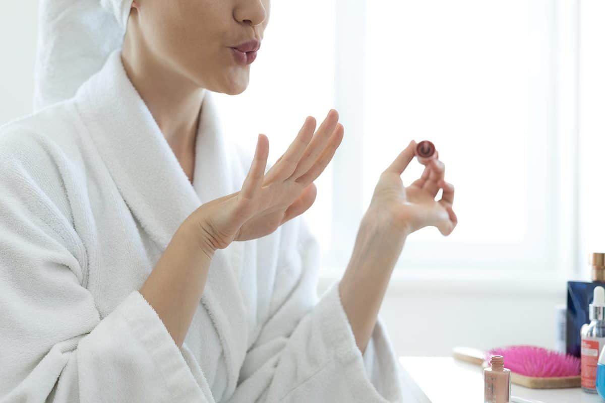 Young woman blowing on nails after applying nail polish