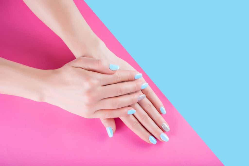 Рука молодой женщины с нежно современным синим маникюрным лаком для ногтей