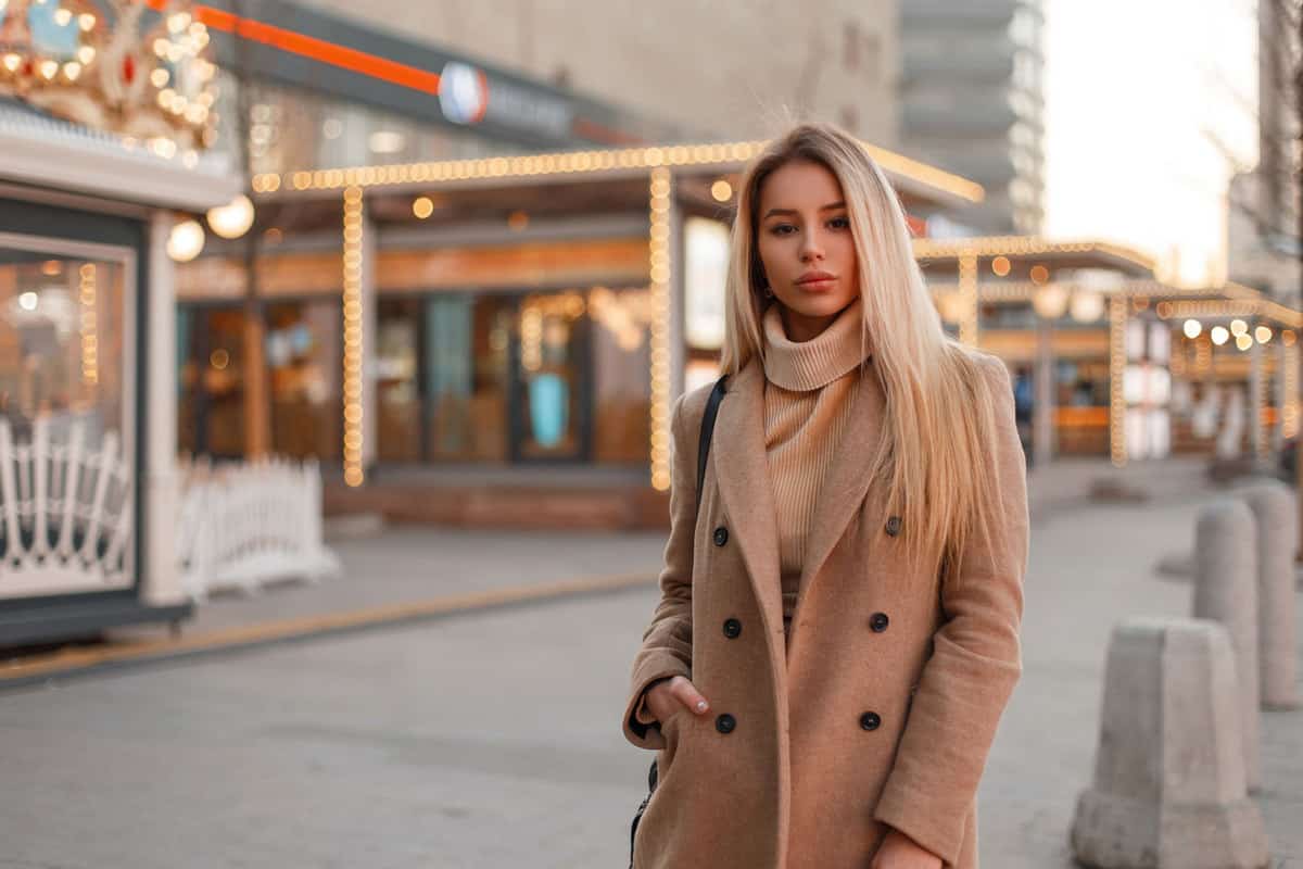 A gorgeous blonde woman wearing a beige coat and a matching beige sweater