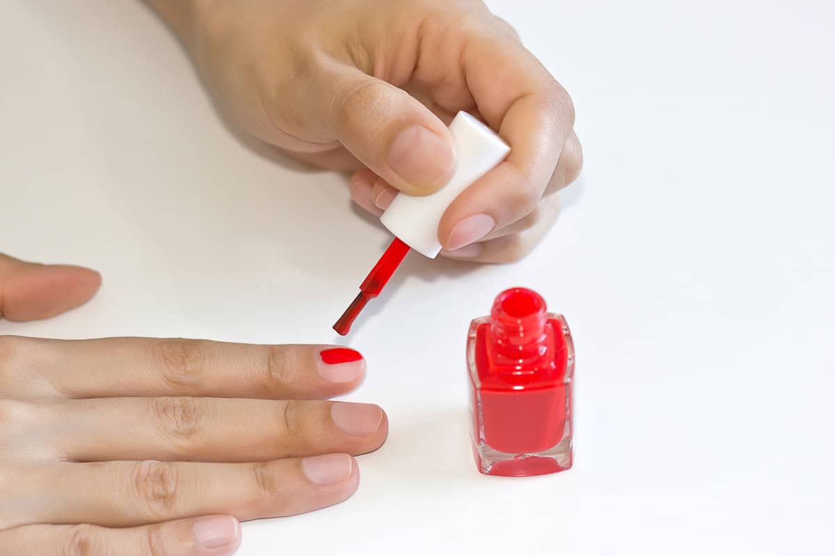 Applying red nail polish on her nails