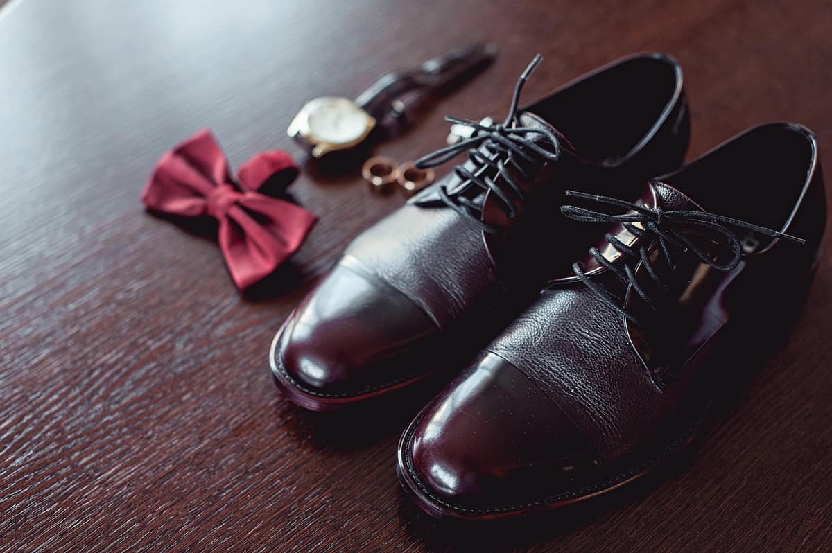 Close up of modern man accessories. wedding rings, cherry bowtie, leather shoes, watch and cufflinks