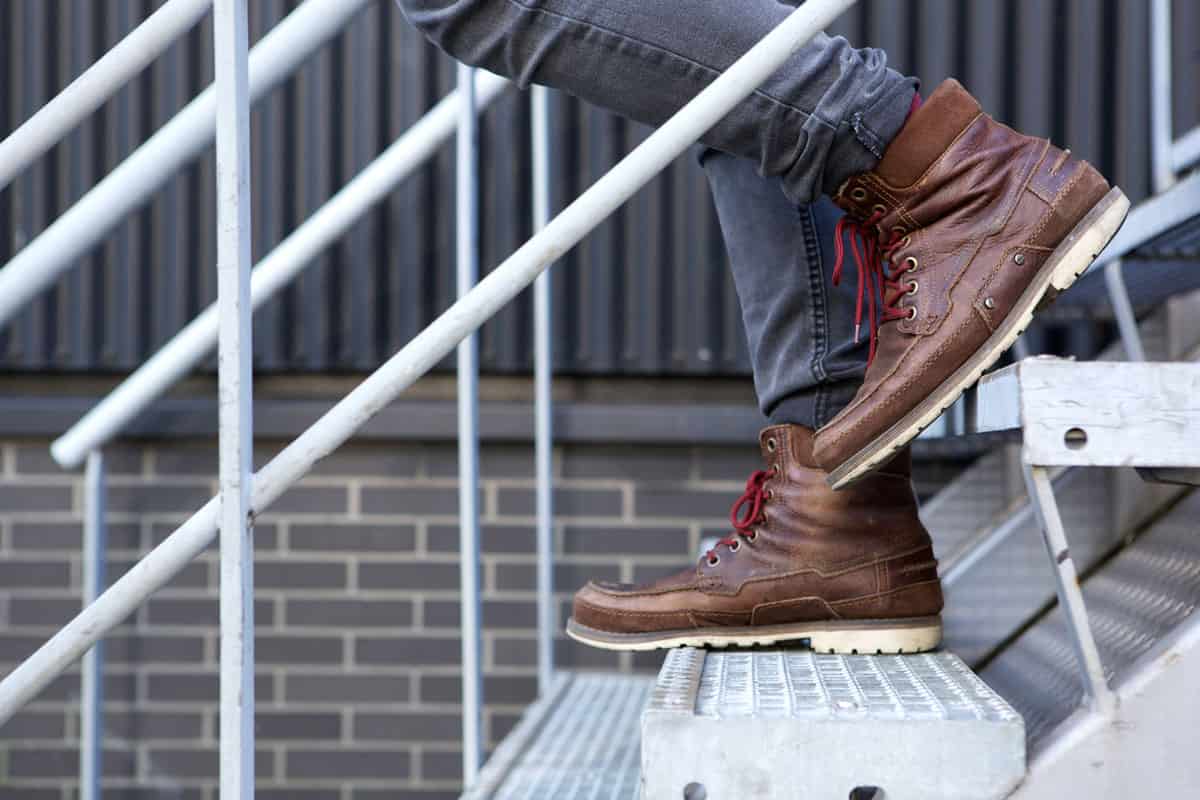 Side view of a male walking downstairs using boots as fashion