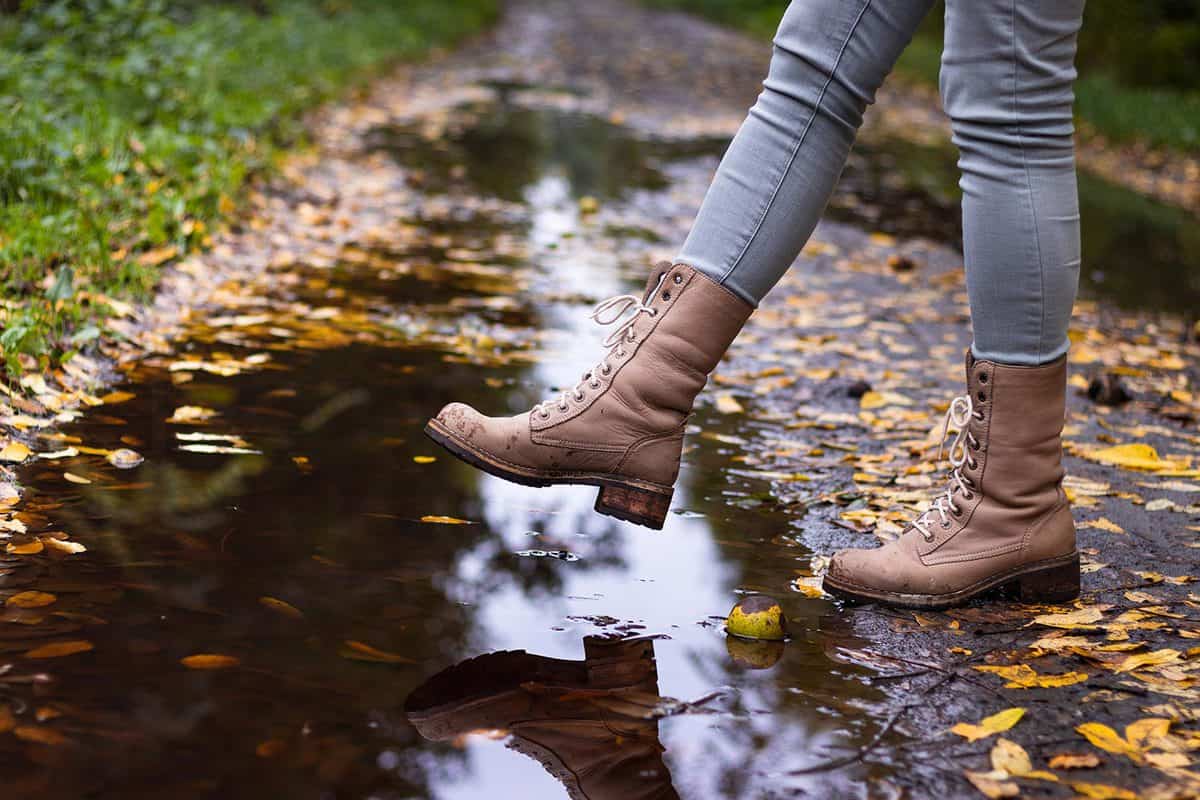 Waterproof leather boots over puddle with reflection