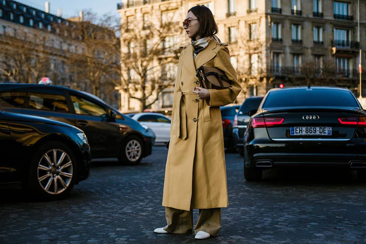 Woman wears sunglasses and a yellow trench coat