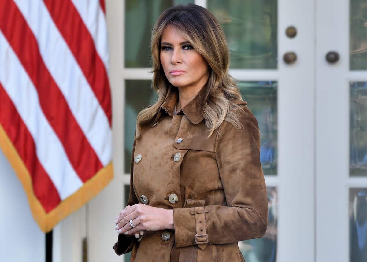 Melania Trump stands with a solemn disposition