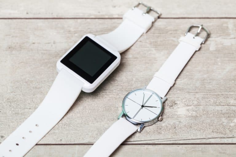 An image of a smart watch lying next to a normal analog watch.