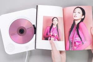 Fan hands holding BlackPink BORN PINK 2nd Album photobook with Jennie on grey, Take Balletcore To The Next Level With Blackpink "Jensetter" Jennie's Ribbon Hairstyle