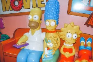The Simpsons figures are sitting on the bench watching TV, Did The Simpsons Predict Doja Cat's Red Fashion Statement?