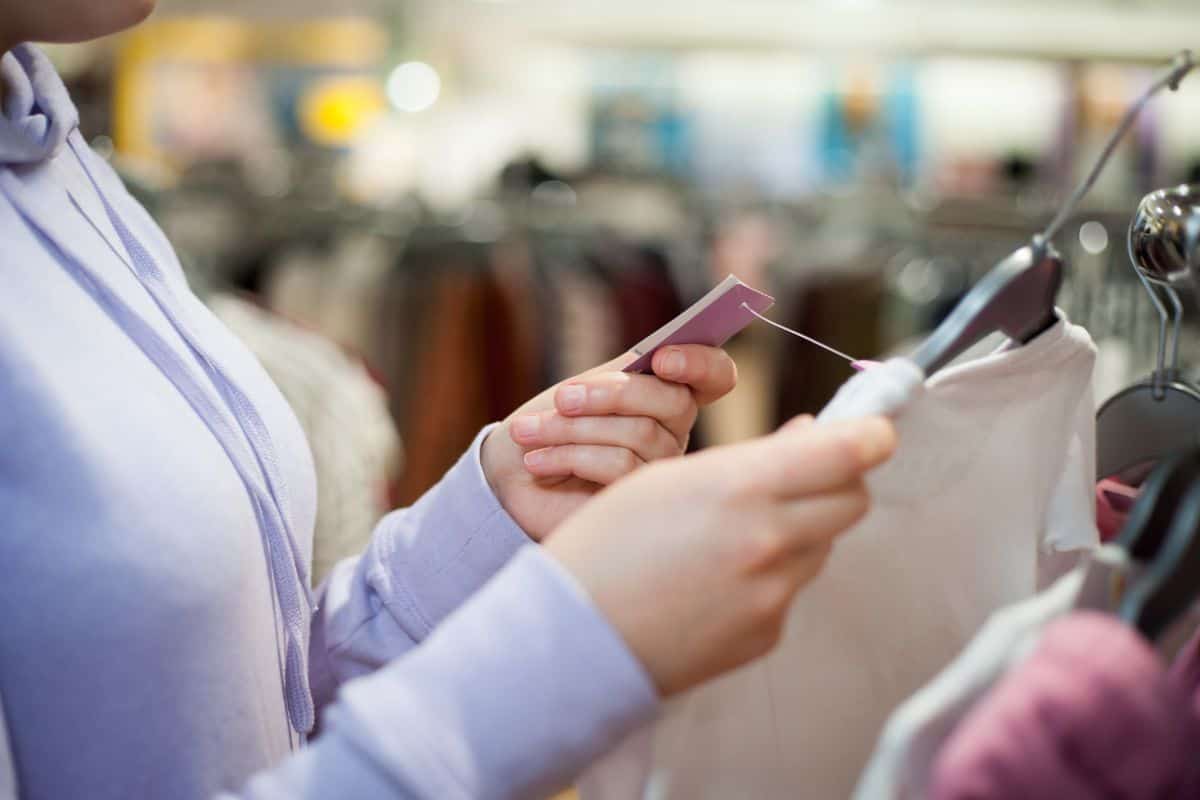 Young woman hands choosing the right clothes for herself and checking prices during sale time