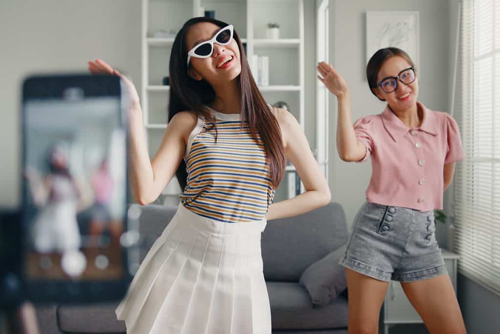 Young woman with her friend tiktoker creating dancing video by smartphone