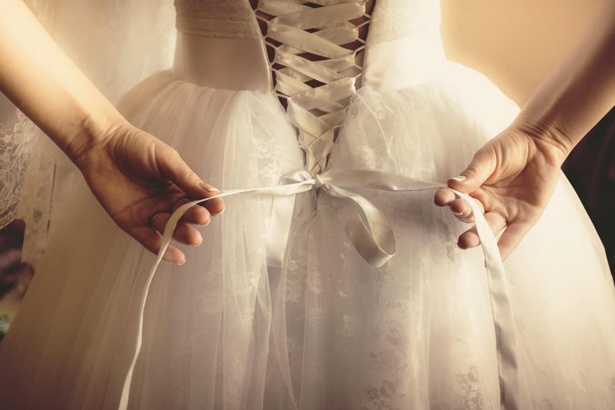 beautiful bride tying up her wedding dress