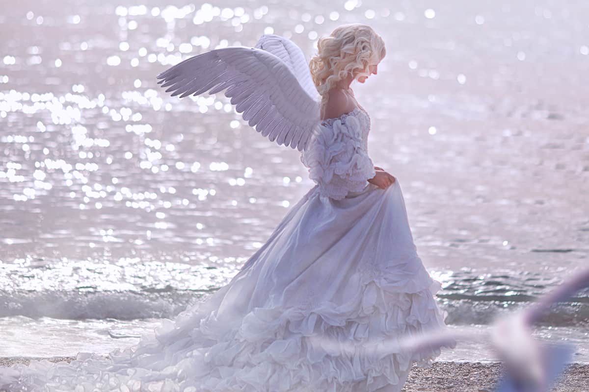 Beautiful girl with angel wings is walking along the seashore