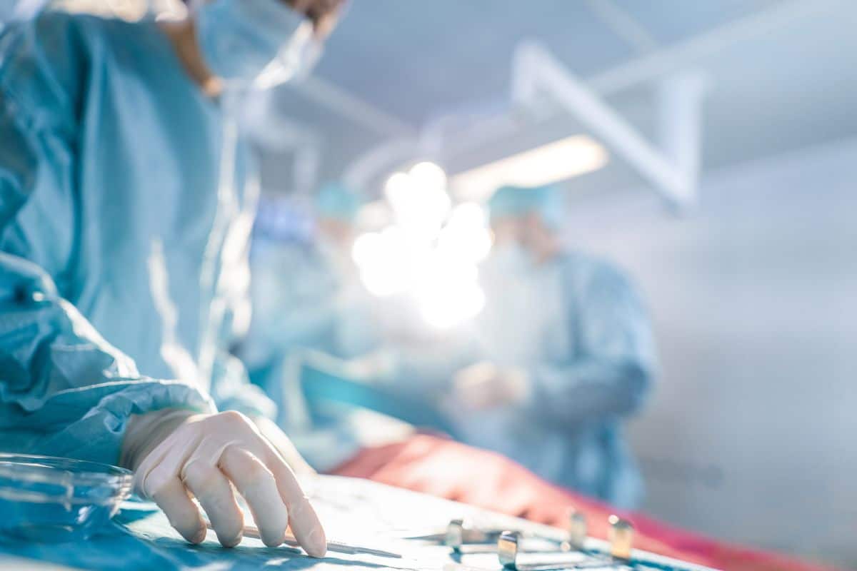 Close-up Shot in Operating Room of Surgical Table with Instruments, Assistant Picks up Instruments for Surgeons During Operation. Surgery in Progress. Professional Medical Doctors Performing Surgery.