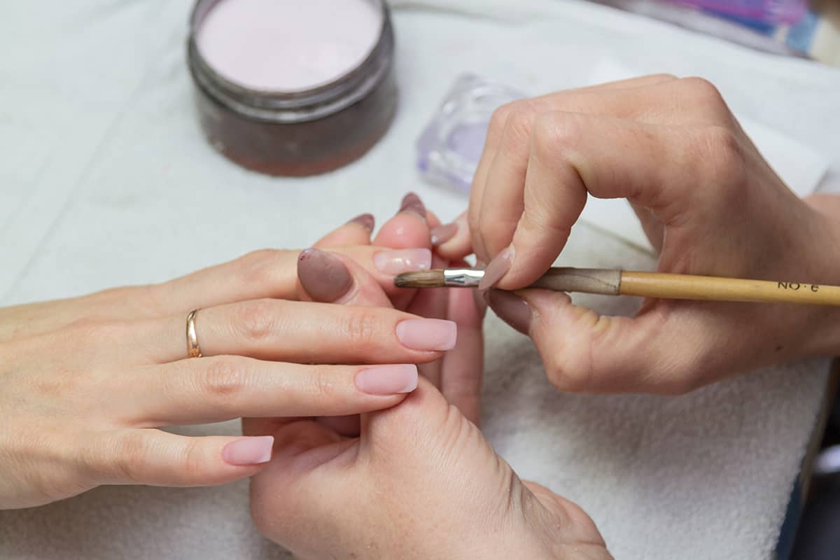 Leveling brush acrylic nails on a specialist in the beauty salon