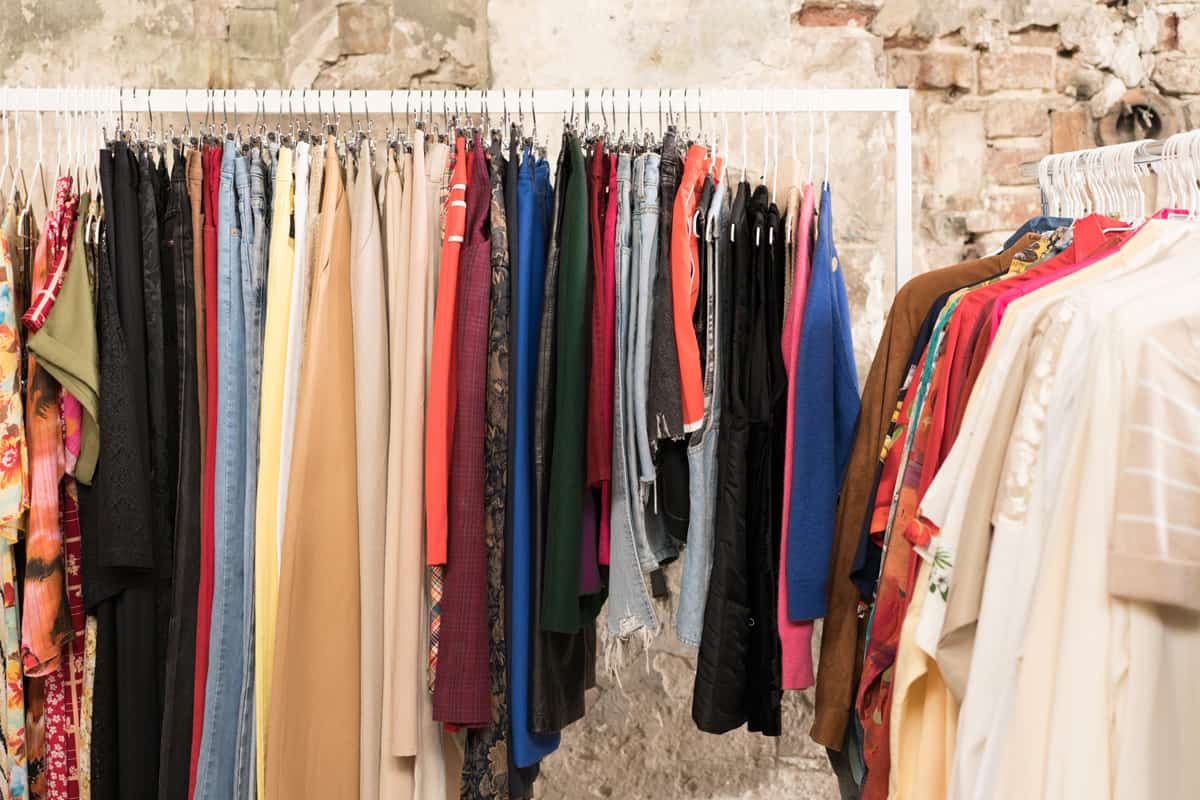 Multicolor clothes on hangers - second hand clothes store or thrift shop