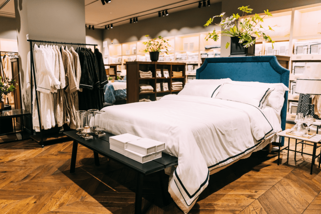 View of assortment of decor for interior shop in store of shopping center. View of bed with linen, bed linen, pillows, plaid. View of home accessories for bedroom in shop fashion retail store. Home
