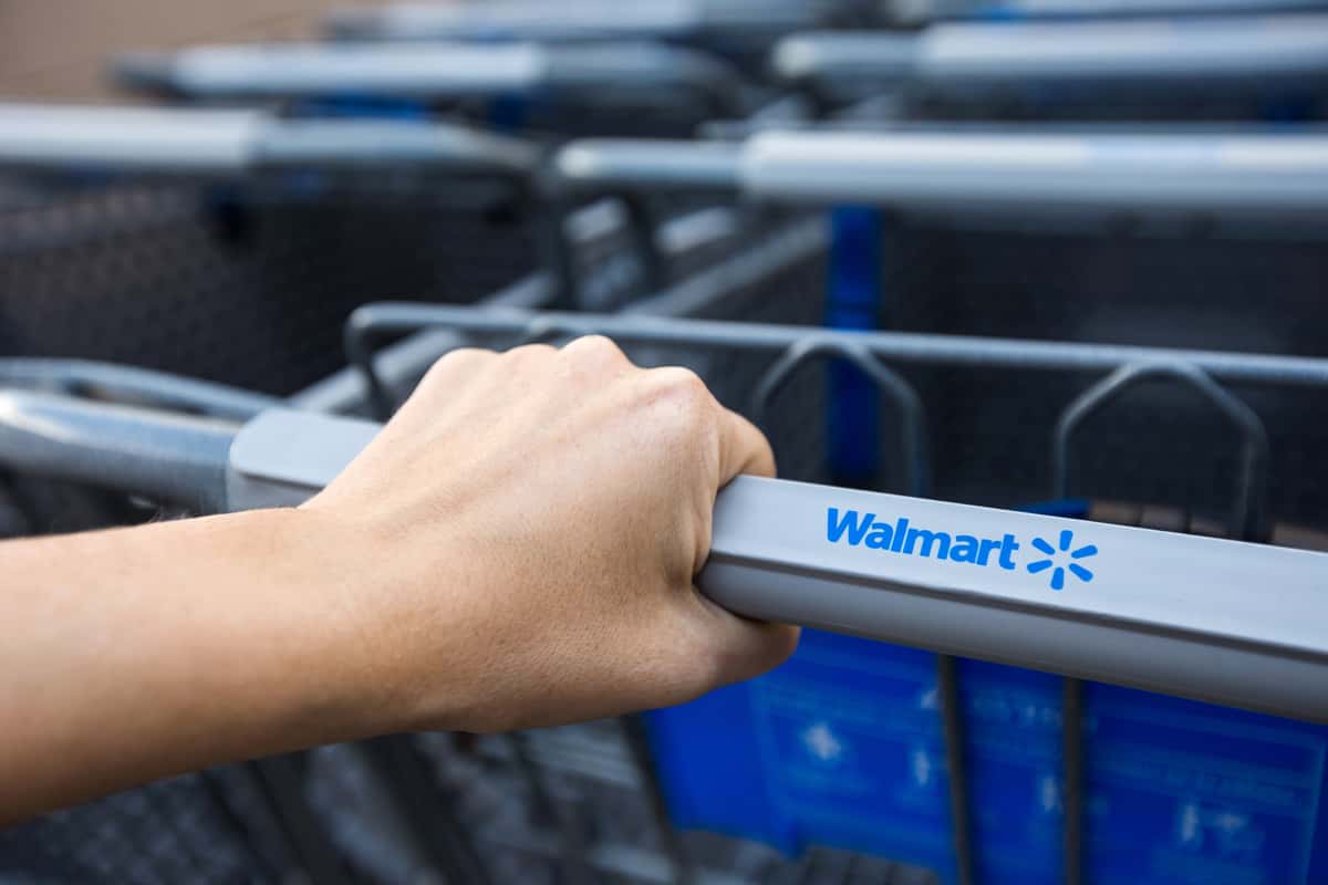 Woman taking shopping cart near supermarket Walmart