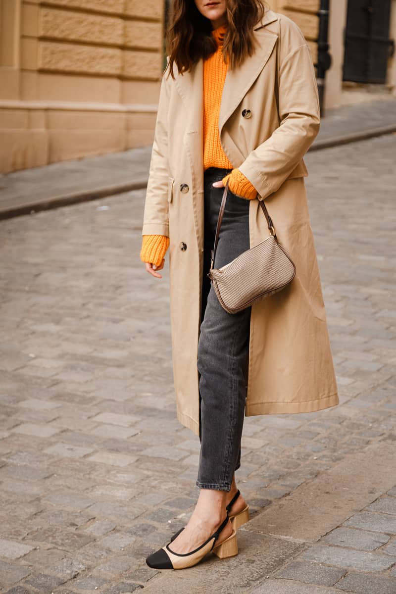 authentic street style portrait of an attractive woman wearing trench coat, sunglasses and slingback shoes, crossing the street.fashion outfit details perfect for autumn fall winter