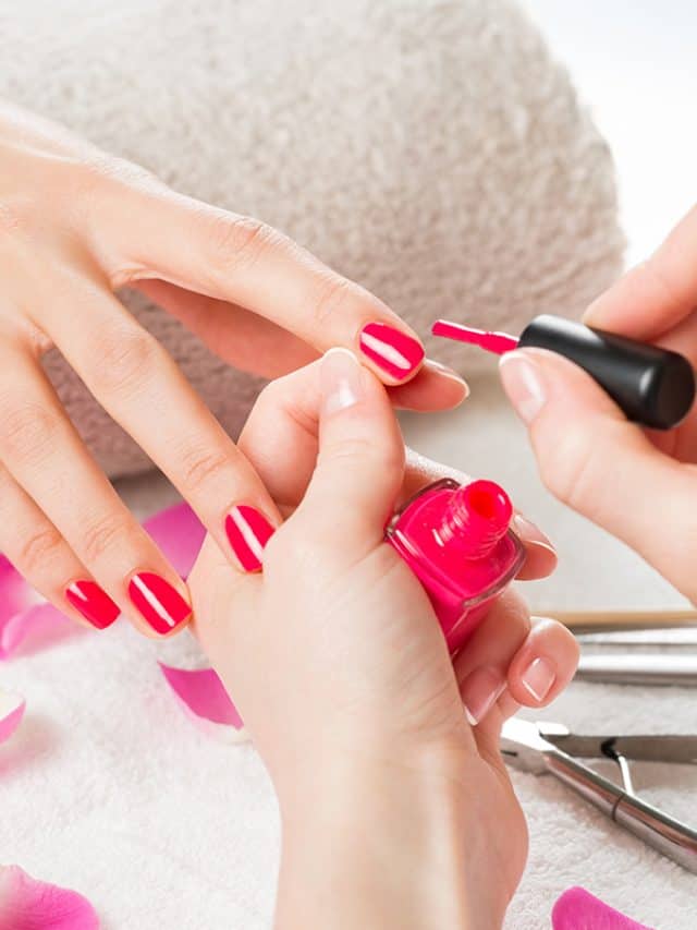 Beautician applying nail polish to female nail in a nail salon