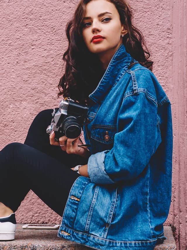 Confident young woman with curly long hair wearing denim jacket