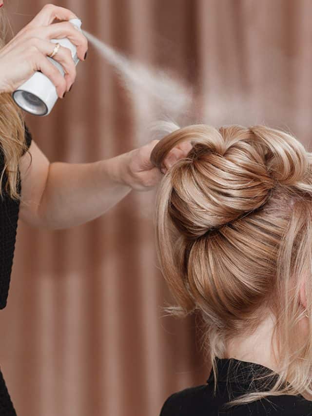 Professional hairdresser using hair spray on client business woman hair at beauty salon